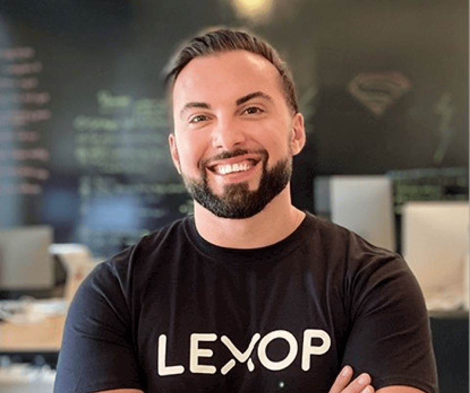 Lexop CEO Amir Tajkarimi  pictured from chest up. He's smiling with arms crossed, wearing a black t-shirt with Lexop written on it. 